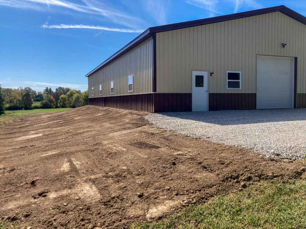 A bulldozer pushing a large metal pipe through muddy ground for drainage solutions.